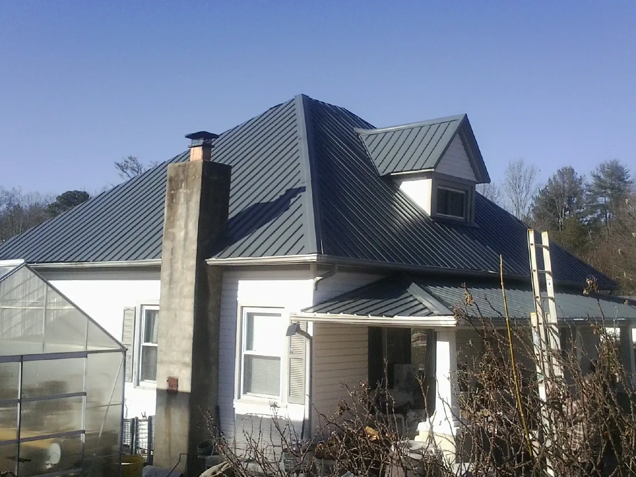Dark blue standing seam metal roof on a white farmhouse with dormer — Slate & Tile Roof Repair by Roofing Brothers in Harwich