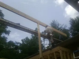 Carpenter setting a ridge beam over a new addition frame — Ice Dam Removal by Roofing Brothers in Harwich