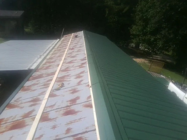 Old rusted panels beside newly installed green metal roofing — Wind Damage Roof Repair by Roofing Brothers in Harwich