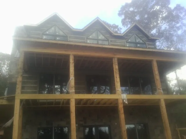 Dormers and porch framing on a large log home under construction — Roof Coating work by our crew in Harwich