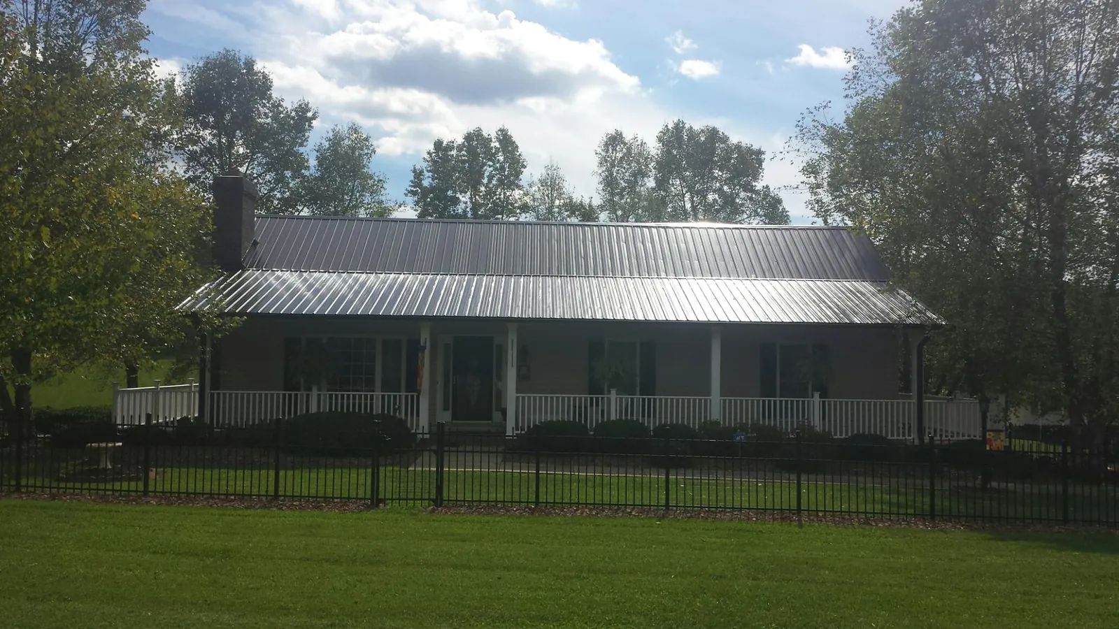 Gray metal roof on a brick ranch with a full width front porch — Gutter Guard Installation work by our crew in Harwich