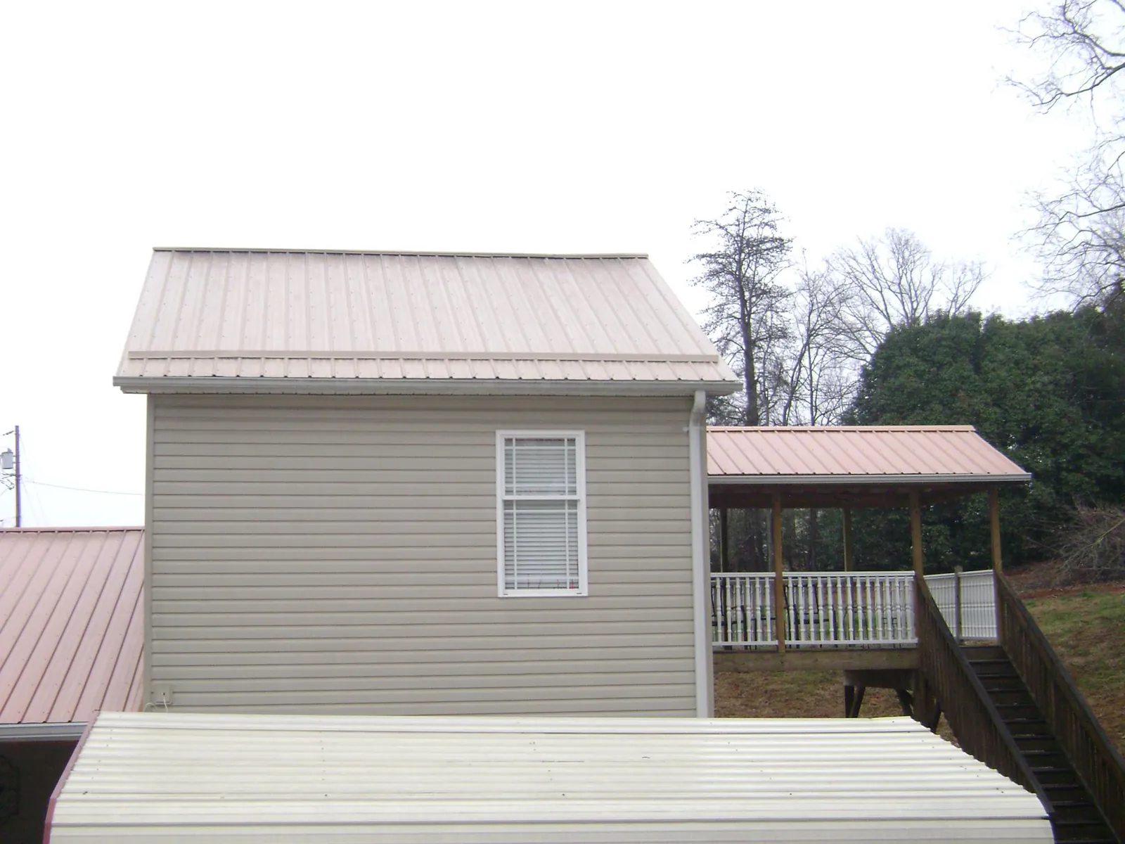 Tan metal roofs on a two story addition and attached porch, from a Roof Replacement job in Harwich