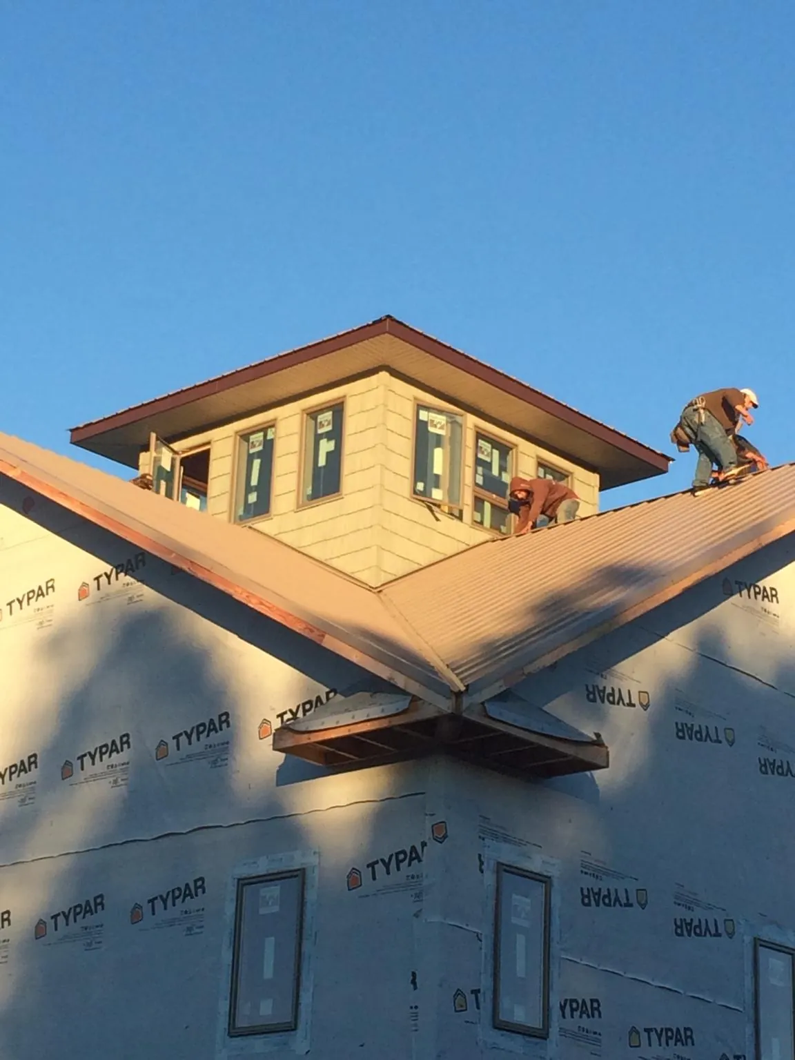 Roofers working around a rooftop cupola on a new metal roof at sunset — Roof Waterproofing in Harwich by Roofing Brothers